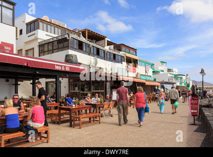 Touristen an Strandpromenade gesäumt von Outdoor-Restaurants und Bars im Küstenort Playa Blanca Lanzarote Kanarische Inseln Stockfoto