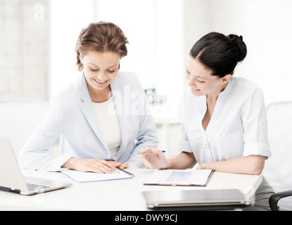 zwei lächelnde Geschäftsfrauen, die im Büro arbeiten Stockfoto
