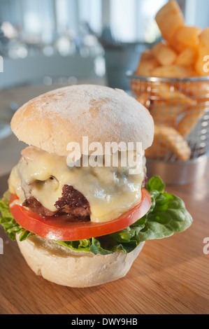 Klassische Beefburger mit Salat, Speck und Käse, serviert mit einer Beilage des französischen gebratenen Kartoffeln oder Pommes Frites. Stockfoto