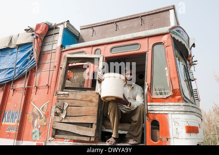 1 indischer Mann sitzen im LKW und zeigt Öl-Eimer Stockfoto