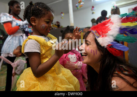 Tel Aviv, Israel. 14. März 2014. Eine israelische freiwillige (R) feiert die bevorstehenden Purim mit Kindern afrikanische Asylbewerber in einem Kindergarten in Tel Aviv, Israel, am 14. März 2014. Purim, feierte in diesem Jahr vom 15. März bis Einbruch der Dunkelheit, 16 März, Sonnenuntergang ist ein jüdischer Feiertag, der die Befreiung des jüdischen Volkes im antiken Perserreich erinnert, wo ein Grundstück gebildet worden war, um sie zu zerstören. © Gil Cohen Magen/Xinhua/Alamy Live-Nachrichten Stockfoto