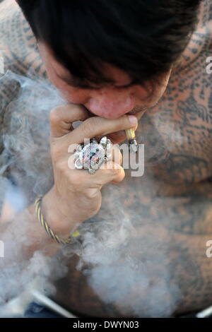 Bangkok. 15. März 2014. Ein Devotee raucht während des jährlichen Tattoo Festival am Wat Bang Phra in Nakhon Pathom Provinz von Thailand, 15. März 2014. Tausende Gläubige aus ganz Thailand und dem Ausland gereist, um das jährliche Tattoo Festival in Nakhon Pathom Provinz zu besuchen. Bildnachweis: Gao Jianjun/Xinhua/Alamy Live-Nachrichten Stockfoto