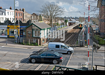 Fahrzeuge, die Überquerung der Bahnlinie in Reigate Stellwerks- und Station in Surrey, UK Stockfoto