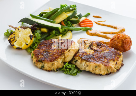 Zwei große Pfanne gebratene Krabbenkuchen serviert mit frischem Gemüse und Hush Welpen. Stockfoto