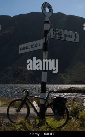 Eine schwarze Tourenrad gegen eine Richtung Straße Post Wastwater See in der Seenplatte, Cumbria, England Stockfoto