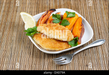 Horizontale Foto von gebratenen Golden paniert beschichtet Fisch und Süßkartoffeln auf weißen Teller Stockfoto