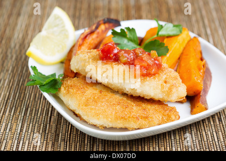 Closeup horizontale der goldenen knackig gebratenen Kabeljau mit Salsa-Sauce an der Spitze mit Yam Fries im Hintergrund Stockfoto