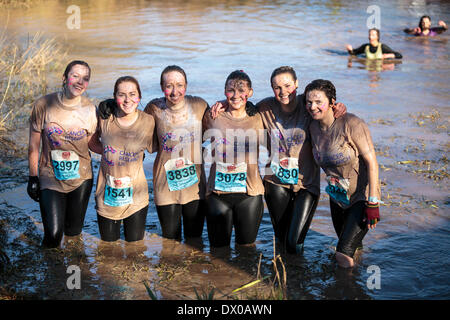 Ein Team von Frauen posieren für ein Foto zwischen waten durch schlammiges Wasser auf ein Hindernis-Parcours im Escot Park in der Nähe von Exeter Devon am 15. März 2014. Das Team gab Geld für Cancer Research UK anheben. Über 3.500 Teilnehmer trat das Ereignis, das Fitness und den Teamgeist fördert. Stockfoto