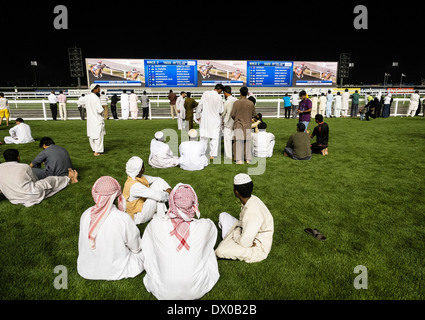 Zuschauer beobachten Rennen am Pferd Rennen treffen auf Al Meydan Racecourse in der Nacht in Dubai Vereinigte Arabische Emirate Stockfoto