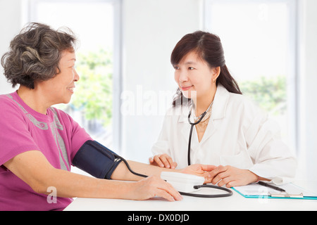 Arzt Blutdruckmessung senior Frau zu Hause Stockfoto