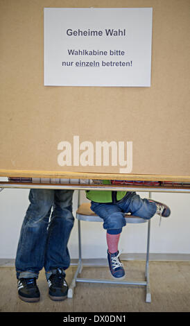 München, Deutschland. 16. März 2014. Ein Mann wirft seine Stimme neben seinem Kind in einem Wahllokal in München, Deutschland, 16. März 2014. Menschen in Bayern werden gebeten, ihre Stimme bei den Kommunalwahlen am 16. März abgeben. Foto: Sven Hoppe/Dpa/Alamy Live News Stockfoto