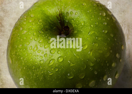 Makro-Ansicht eines grünen Apfels gegen hellgrünen strukturierten Hintergrund. Stockfoto