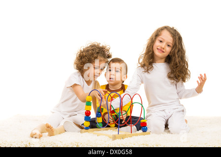 Drei Kinder nach Hause zu spielen, mit Holzspielzeug und sitzen auf Teppich Stockfoto