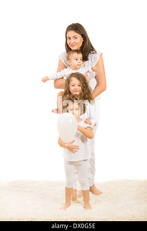 Glückliche Mutter und drei Kinder stehen auf Teppich zu Hause, in einer Linie, die isoliert auf weißem Hintergrund Stockfoto