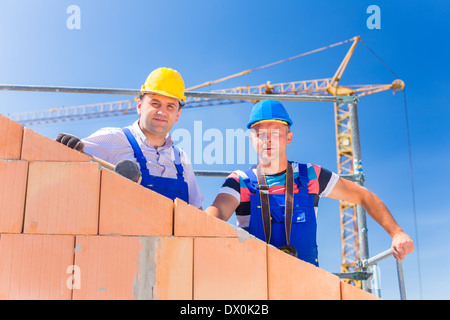 Zwei stolze Bauarbeiter Website oder Maurer auf Hausprojekt Regie des Krans mit einer Fernbedienung Stockfoto