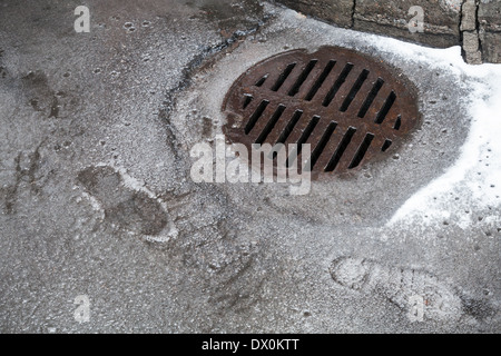 Kanal-Schacht auf der städtischen Asphaltstraße mit nassem Schnee Stockfoto