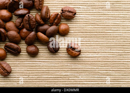 Hintergründe und Texturen: dunkel geröstete Kaffeebohnen auf grobe Leinwand Oberfläche verstreut Stockfoto