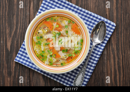 Hühnersuppe mit Nudeln, Farfalle in der Schüssel auf Holztisch Stockfoto