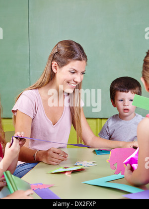 Kindergärtnerin im Kindergarten tun Künste & Handwerk mit Kindergruppe Stockfoto