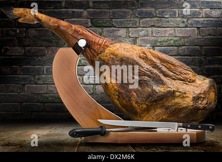 Ein Vorderbein Serrano-Schinken auf einem Holzständer auf künstlerischen Hintergrund abgebildet. Stockfoto