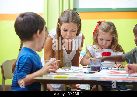 Andere Kinder im Kindergarten mit Pinsel und Wasserfarben malen Stockfoto