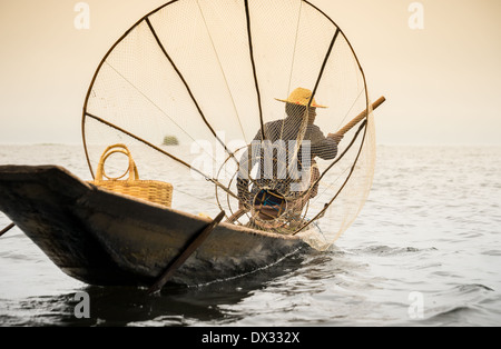 INLE-See, MYANMAR - ca. Dezember 2013: Fischer mit typischen Net und Boot in der Inle See, Myanmar Stockfoto