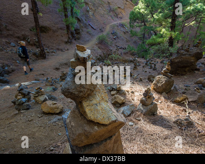 Eine weibliche Wanderer geht Steinhaufen, die auf der Strecke im Nationalpark Caldera de Taburiente stehen. Stockfoto