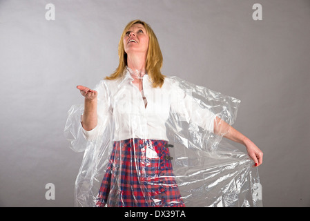 Frau mit durchsichtigen Kunststoff Poncho Mac Regentropfen wird gesucht Stockfoto