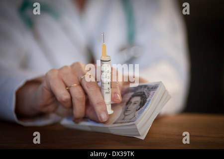 Nahaufnahme einer Ärzte-Hand halten Bargeld und eine Injektionsspritzen Stockfoto