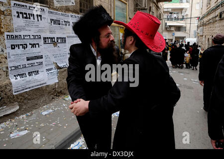 Ein hasidischer Jude, der während des jüdischen Urlaubs von Purim in Mea Shearim, einer ultraorthodoxen Enklave in Westjerusalem Israel, einen Shtreimel Pelz-Hut trägt, der mit einem Haredi-Juden tanzt, der einen Cowboy-Hut trägt Stockfoto