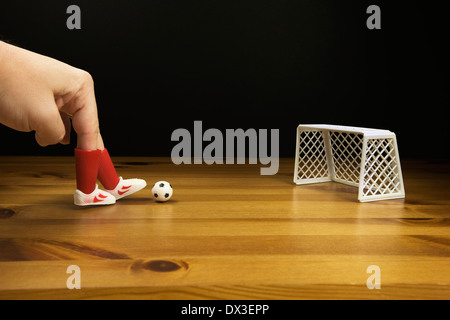 Ein Personen-Finger in Kunststoff Football Boots spielen Tischfußball auf einem Holztisch, Stockfoto