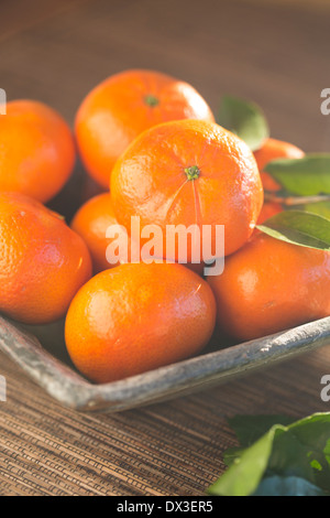 Mandarinen in einer rustikalen blau Schüssel auf eine gewebte Matten, Stockfoto