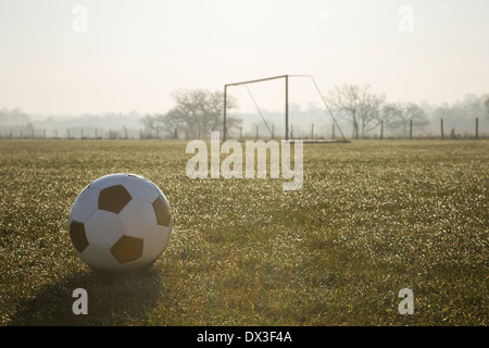 schwarze und weiße Fußball auf einem leeren Fußballplatz, frostigen winter Sonnenaufgang am Morgen Stockfoto