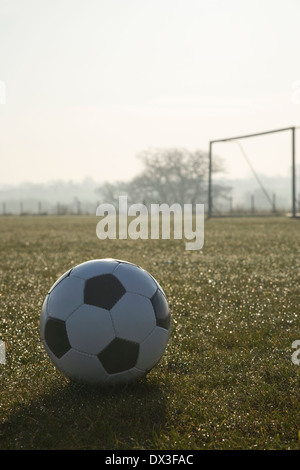 schwarze und weiße Fußball auf einem leeren Fußballplatz, frostigen winter Sonnenaufgang am Morgen Stockfoto