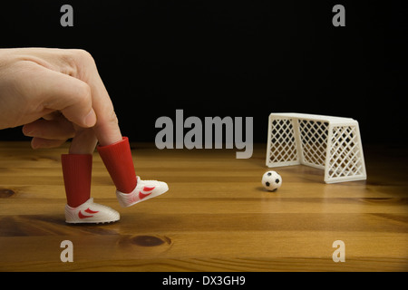 Ein Personen-Finger in Kunststoff Football Boots spielen Tischfußball auf einem Holztisch, Stockfoto