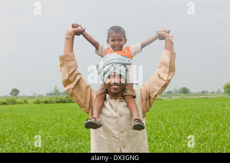 Indische Bauern tragen seines Sohnes in landwirtschaftlichen Betrieben Stockfoto