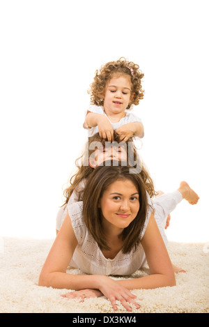 Mutter und Tochter am Fell Teppich an der Spitze aufeinander liegen und Spaß Stockfoto