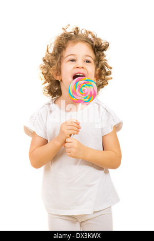 Glückliche kleine Mädchen mit dem lockigen Haar lecken einen großen Lutscher isoliert auf weißem Hintergrund Stockfoto