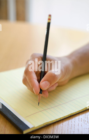 Mannes Hand mit Bleistift über Notizblock am Schreibtisch, Nahaufnahme Stockfoto