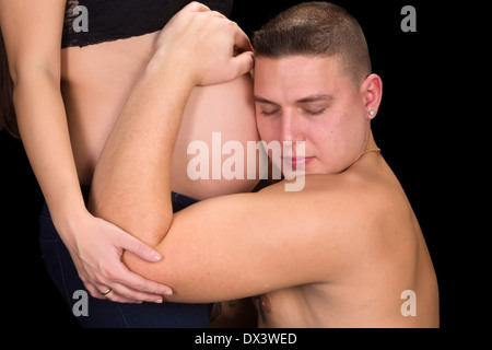 Junger Vater mit seiner Frau schwangeren Bauch in den Händen Stockfoto