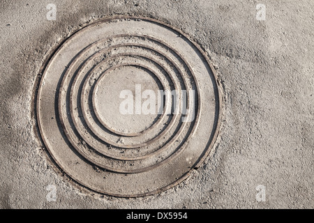 Runde Kanalisation Kanaldeckel auf städtischen Asphaltstraße Stockfoto