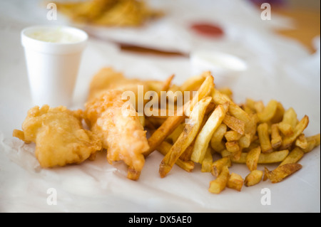 Take-out Fish &amp; Chips auf braunem Papier mit einer Seitenlänge von Krautsalat in einer Styropor-Tasse Stockfoto