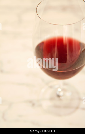 Rotwein im Weinglas auf weißem Hintergrund, erhöhte Ansicht, Nahaufnahme Stockfoto