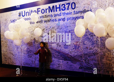 Petaling Jaya, SELANGOR, MALAYSIA. 18. März 2014. Ein Junge spielt mit Ballon vor der riesigen Wand wollen/beten während einer Veranstaltung für die fehlenden Malaysia Airline, MH370, in einem Einkaufszentrum in Petaling Jaya, Malaysia, am 18. März 2014. Eine Koalition aus 26 Ländern, darunter Thailand, sind auf der Suche nach Malaysia Airlines Flug 370, die mit 239 Menschen an Bord auf einem Nachtflug von Kuala Lumpur nach Peking 8 März verschwunden. Bildnachweis: Kamal Sellehuddin/ZUMAPRESS.com/Alamy Live-Nachrichten Stockfoto