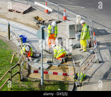 Arbeiter arbeiten auf der Straße, die Verlegung der Pflastersteine im Warnschutz Jacken. Stockfoto