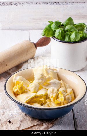 Metallschale hausgemachte Pasta Ravioli und Perle auf Holztisch mit Vintage Becher frisches Basilikum Stockfoto