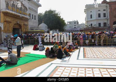 Warteschlange der Anhänger mit einigen sitzen in den goldenen Tempel in Amritsar, als Urlaub, großen Ansturm von Gläubigen Sikh Website besuchen Stockfoto