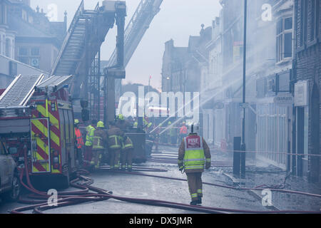 Feuerwehrmänner, die durch Motoren & brennende Gebäude, bekämpfen das Feuer mit Wasserstrahlen aus Schläuchen, Ausgebrannten, geschwärzte Windows - Harrogate, Yorkshire, England, UK. Stockfoto