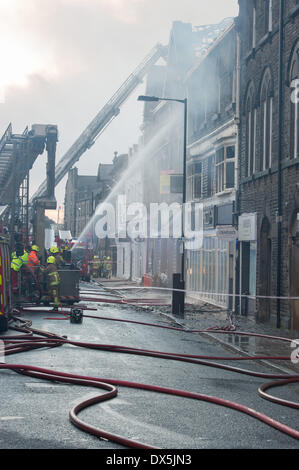 Feuerwehrmänner, die durch Brennen, verrauchten Gebäude, bekämpfen einen Brand mit Wasser Jet am ausgebrannten, geschwärzte Windows - Harrogate, Yorkshire, England, UK. Stockfoto