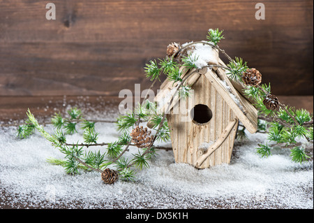 Vogelhaus und Weihnachtsbaum Dekoration Brunch über rustikalen hölzernen Hintergrund. Oldtimer Land Stil Bild mit Schnee Stockfoto